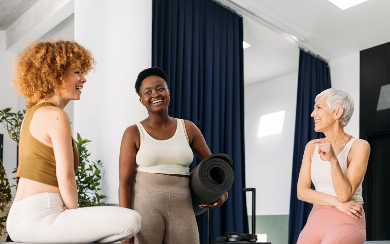 a person holding a yoga mat standing next to a person sitting on a chair